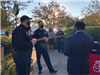 Two police officers talk with a man in a suit at the City Hall courtyard.