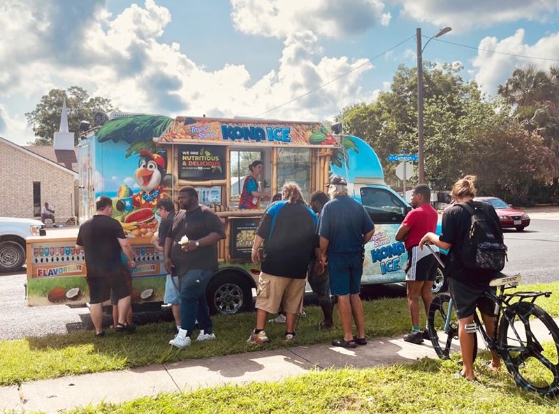 Group of people around Kona Ice truck in Queen City park
