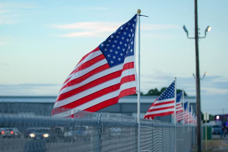 A line of American flags on top of a chain link fence at the community center