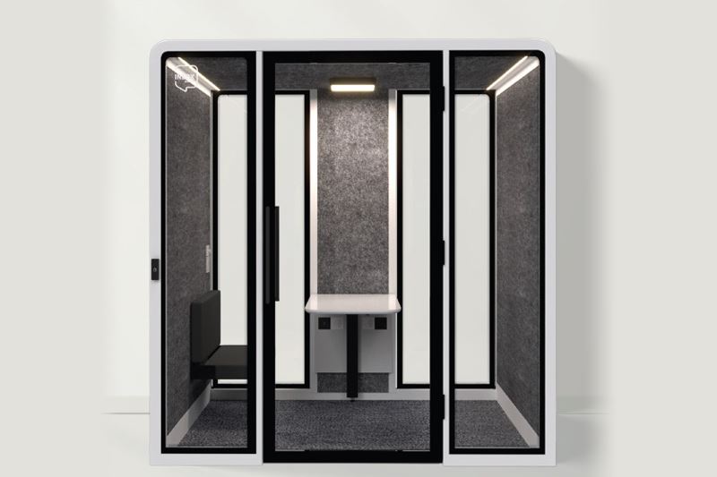 A dark gray and white booth with a work table, bench and overhead lighting.