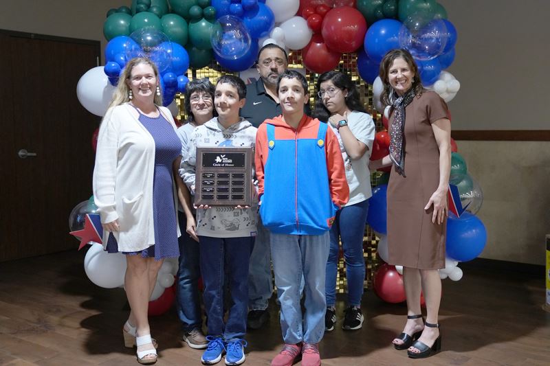 Group photo of a family holding a plaque
