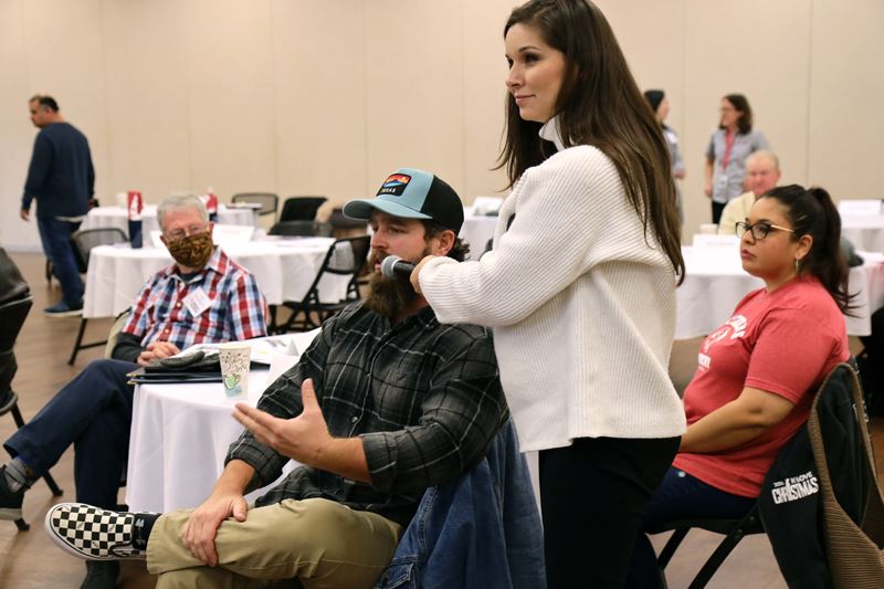 Woman holds a microphone to a man seated at a table.