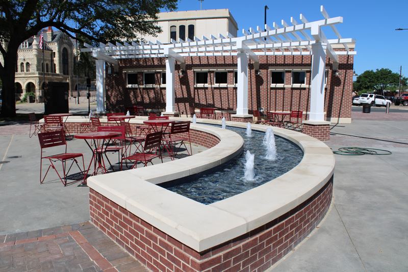 A small brick building with seating and a decorative fountain in the front