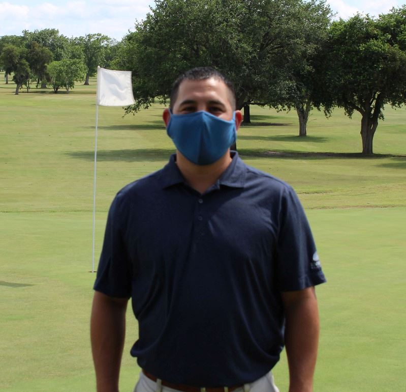 Man wearing facial covering stands on golf course
