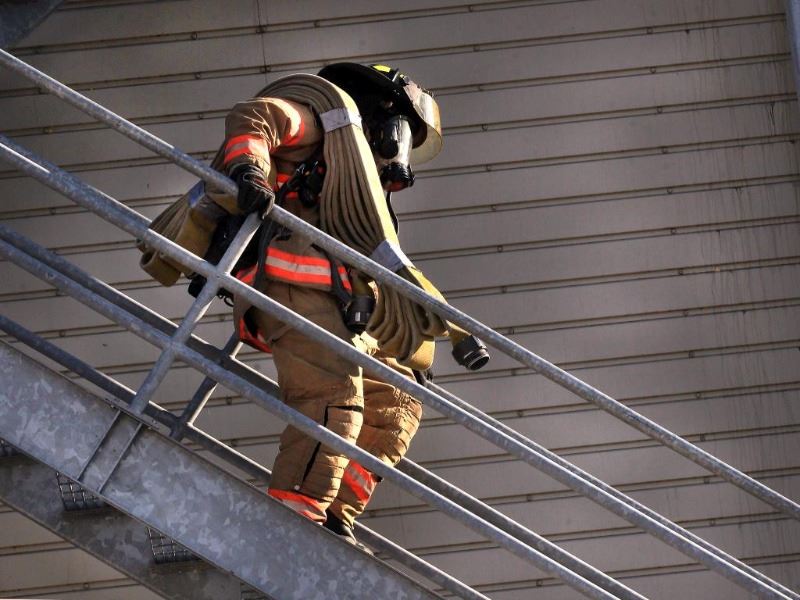 Fire fighter walking down stairs with a hose